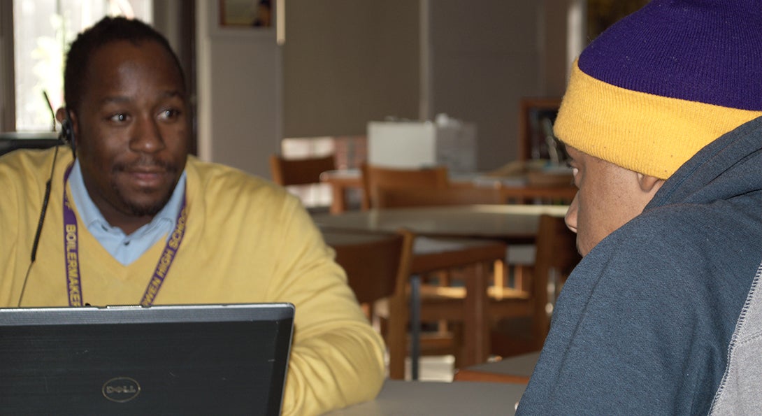 Teacher Eugene Robinson talks one-on-one with a Black male student at CPS Bowen High School, in the school's library.