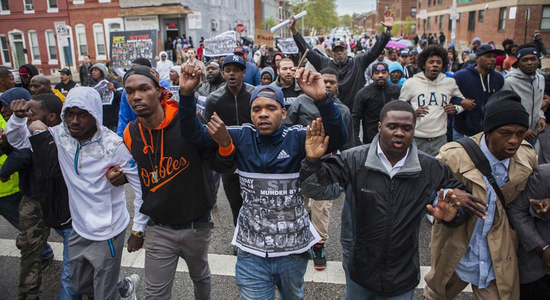 Baltimore citizens march with hands raised as a protest to the police killing of Freddie Gray.