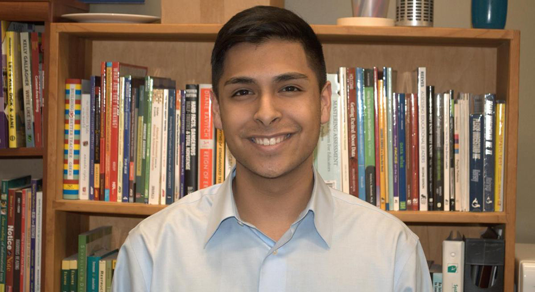Daniel Rocha stands in front of a bookcase in a room in the College of Education building.
                  