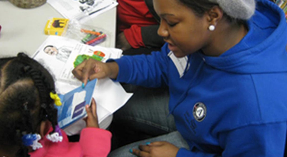 A volunteer reads a book to a young girl at the Center for Literacy's MLK Service Day.
                  