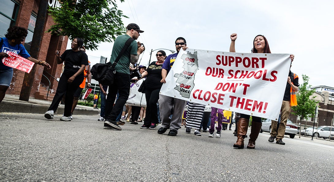 Parents and community activists march through a Chicago street carrying a banner that reads 