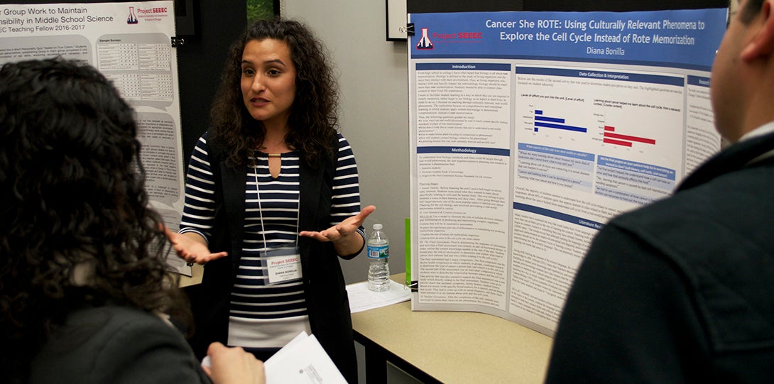 SEEEC Teaching Fellow Diana Bonilla explains her poster presentation to two other fellows.