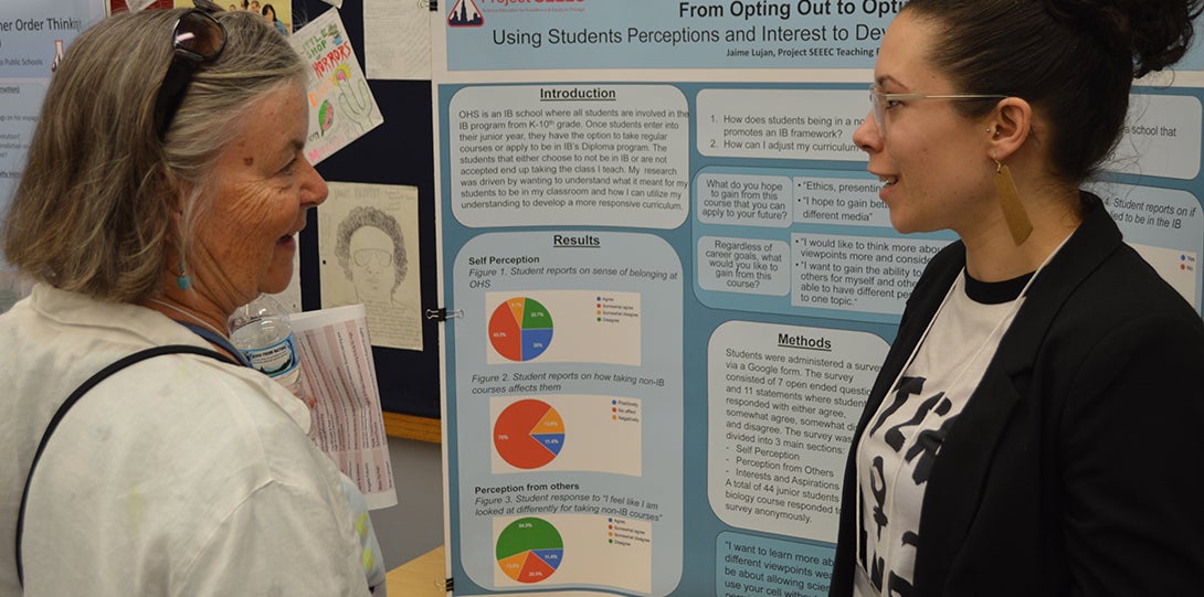SEEEC Teaching Fellow Jamie Lujan explains her poster presentation to a Project SEEEC researcher.