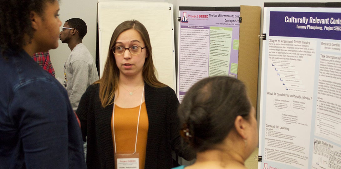 SEEEC Teaching Fellow Tammy Pheuphong talks with a fellow student while standing in front of her poster presentation.