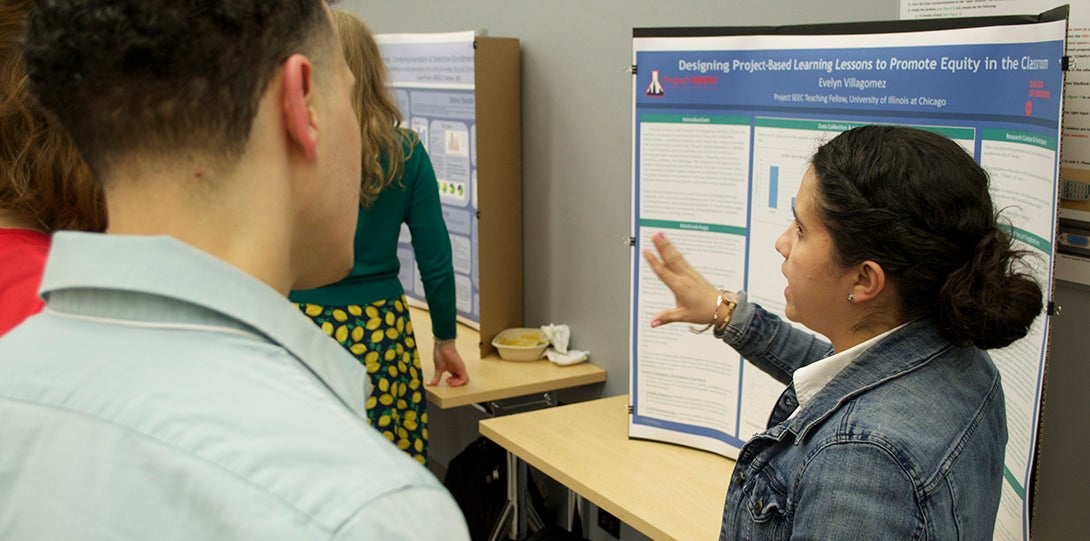 SEEEC Teaching Fellow Evelyn Villagomez gestures with her hands while explaining her poster presentation to another fellow.