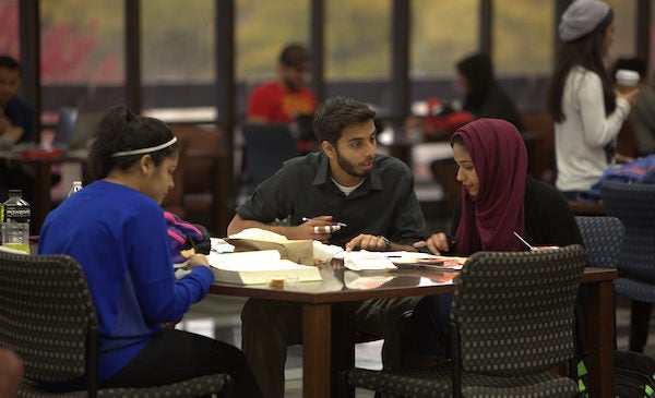 A male and female student discuss their homework sitting at a table in the UIC library.